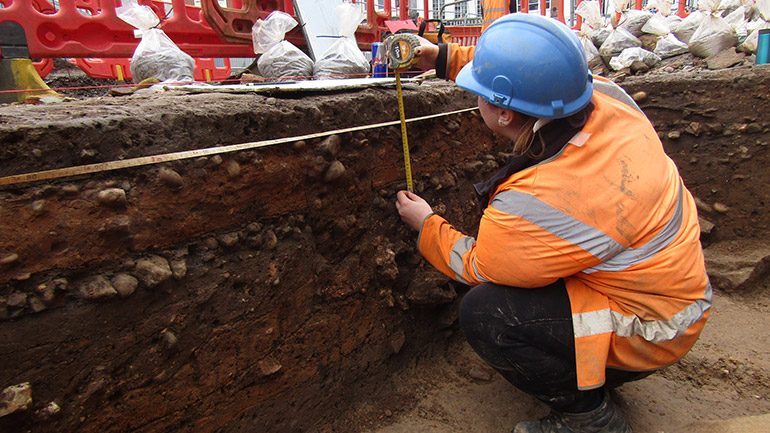 Archaeologist records Roman and medieval layers. Credit: ULAS