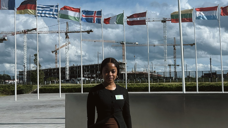 Zewelanji Nalwamba stands in front of national flags and construction cranes outside NATO headquarters in Brussels.