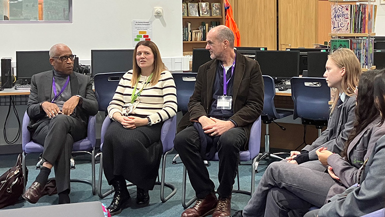 Simon Woolley speaking with students during a discussion in a classroom.