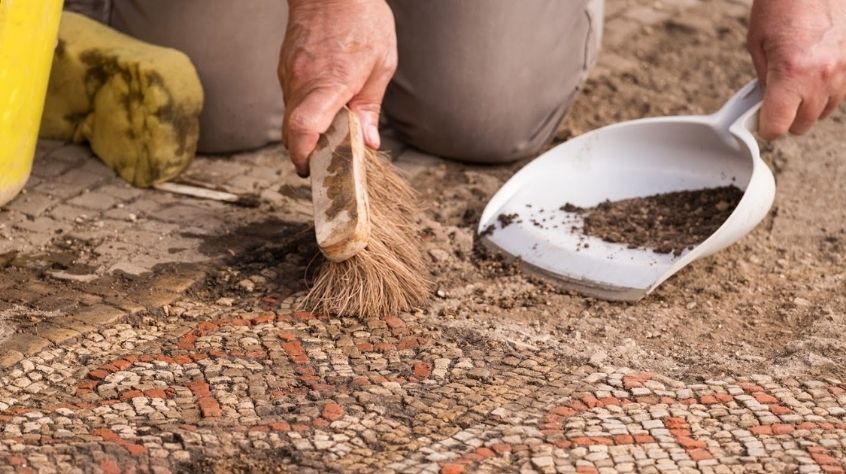 An archaeologist uses a brush to clean a Roman mosaic found in Rutland.