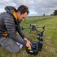 Steve Lloyd in an open field preparing a large drone for flight during a field deployment