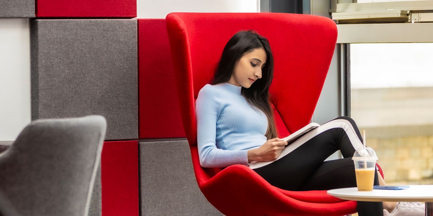 Student sitting in a large chair, reading a book