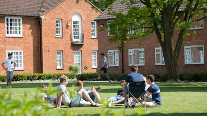 Students sat on the lawn on a warm sunny day outside the accommodation