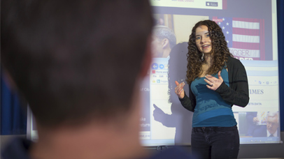 Someone presenting in front of a projector screen