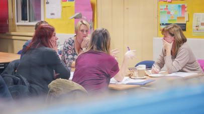 students sat round a desk in conversation