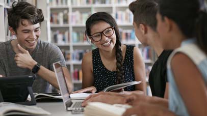 Group of students sat around a table and laughing and smiling.