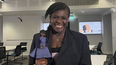 Maggie Aderin-Pocock holding a doll of her likeness