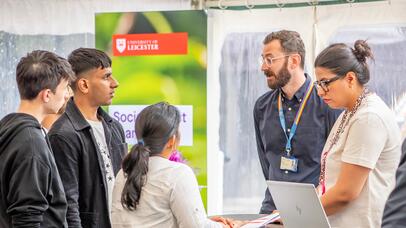 Three students chatting with University of Leicester staff on Campus