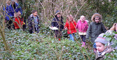 Children and school staff walking through a woodland
