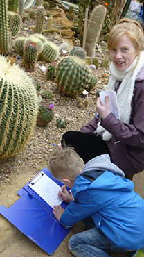 Teacher and children by cacti in the desert house at the university of Leicester Botanic Garden