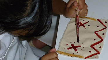 Child painting  a pattern on cloth