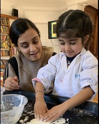 Children with hands in sticky dough with adult watching