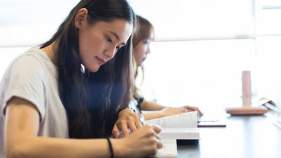 female student writing in notebook