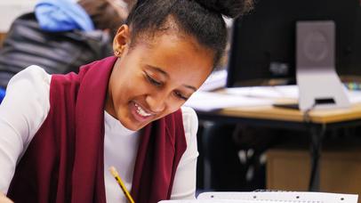 female student writing in notebook in library