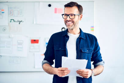 male in blue shirt and black glasses smiling and presenting