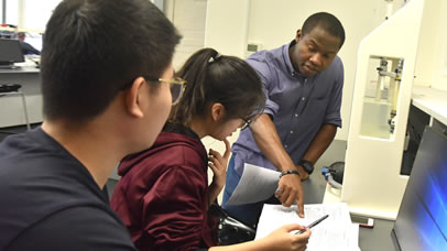 Students being instructed by a teacher in a lab setting