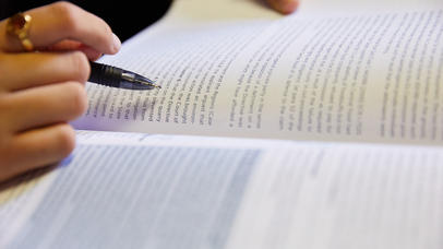 A pen tracing the lines in a textbook
