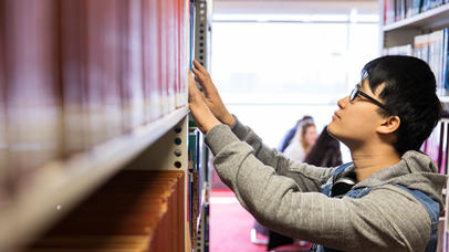 A student browses the library shelves for a book