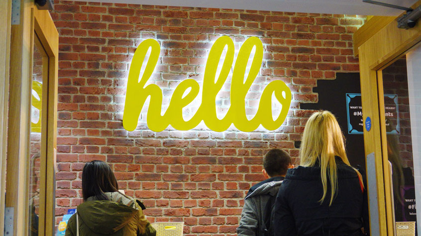 A neon sign which reads 'hello' above a help desk in the University of Leicester Students' Union