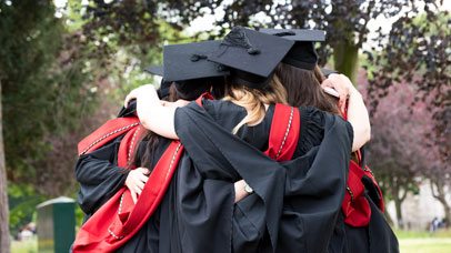 Graduands hugging in their caps and gowns