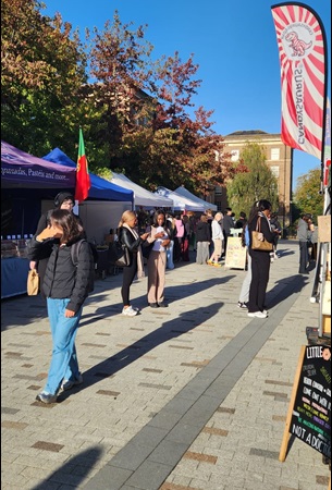 University of Leicester on a bright sunny day, with a group of students visiting outdoor market stalls