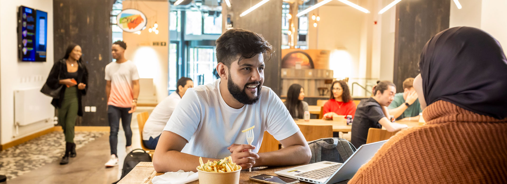 Students sitting at a table in the Students Union with a bowl of chips between them