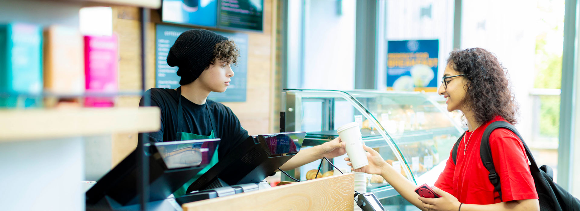 Colleague at Starbucks handing a cup to a student over a counter.