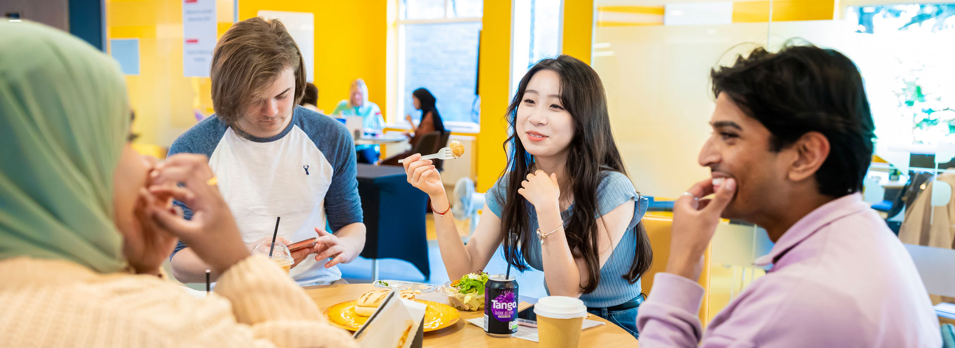 Students sitting around a table, talking and eating.