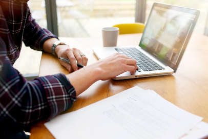 male on laptop surrounded by paper