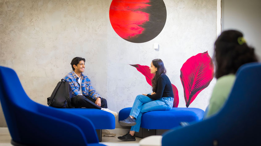 Students sitting on comfy chairs, talking to each other.