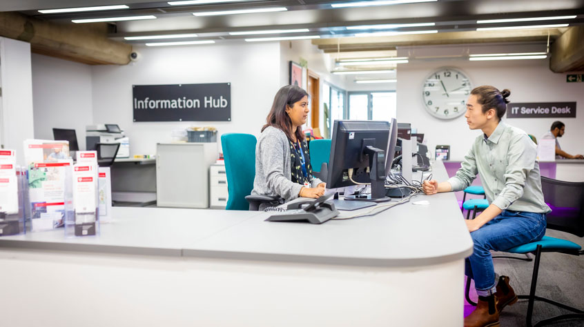 A student getting help at the information hub in the University library.
