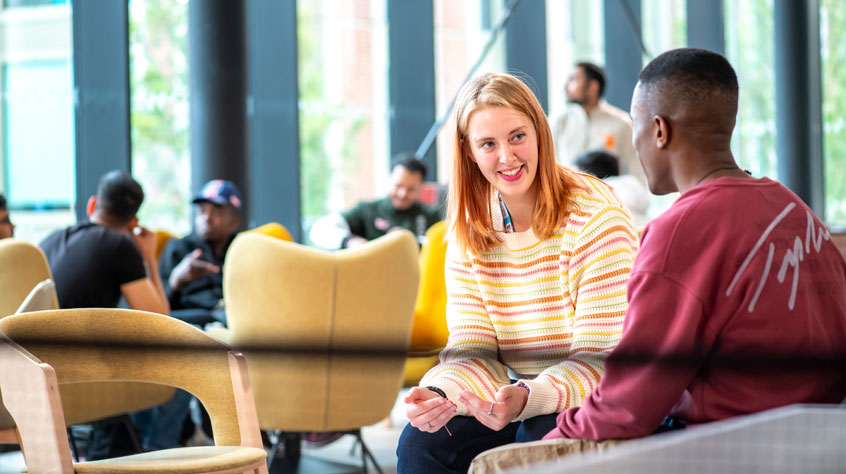 A student and member of staff talking in Freemans Common bar and kitchen