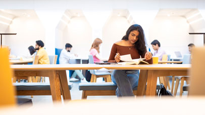 Person sitting at a high table, with people working around her.