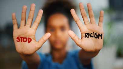 Woman holding out her hands with 'stop racism' written on them.