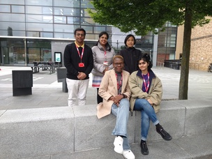 Group of two people sitting and three people standing outside David Wilson Library building