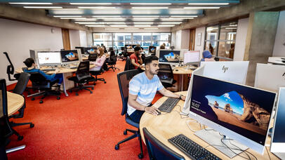 Students working individually and together on computers in a library's open computer lab.