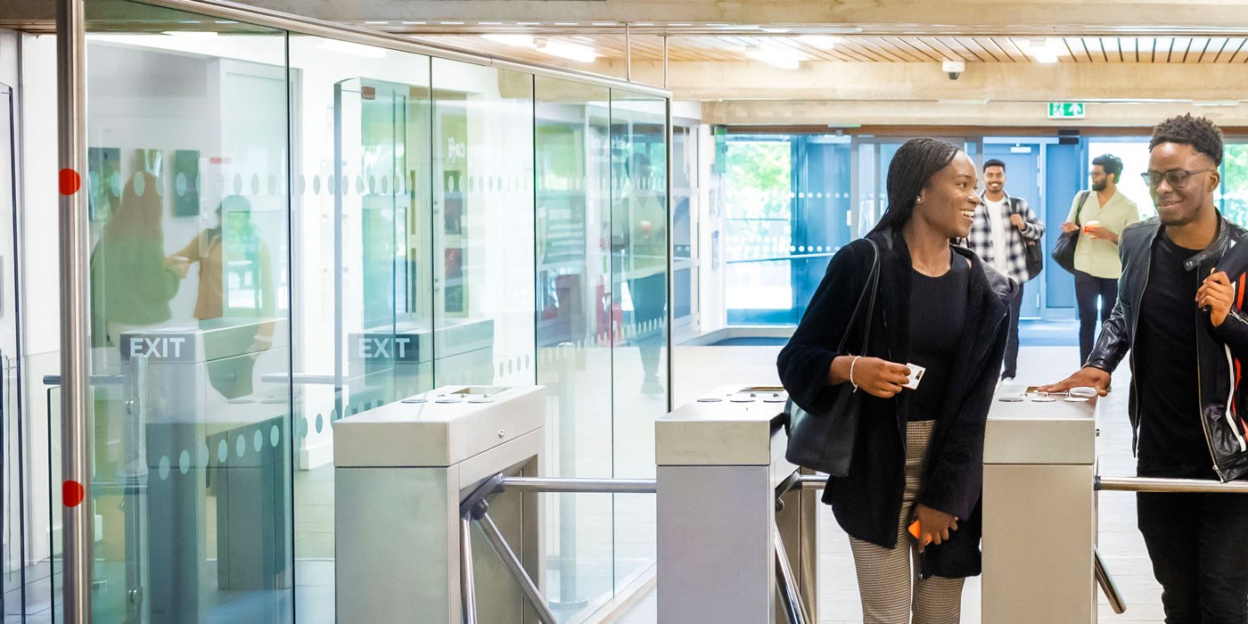 Two students walking through the turnstiles of the David Wilson Library