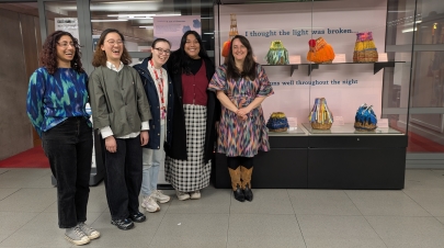 A group of Museum Studies students in front of a display case containing baskets created by artist Jenny Steele