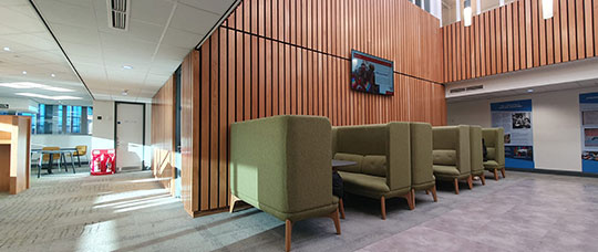 Seating area with green seating in benches with tables between.