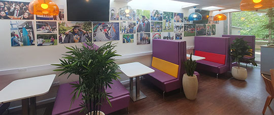 Photograph of empty booths, with many photographs of students across campus on the walls.