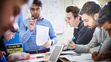 male lecturer talking to small group of students