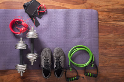 Flatlay of gym equipment including mat, weights, trainers