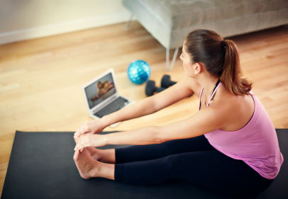 Lady sitting on yoga mat stretching 