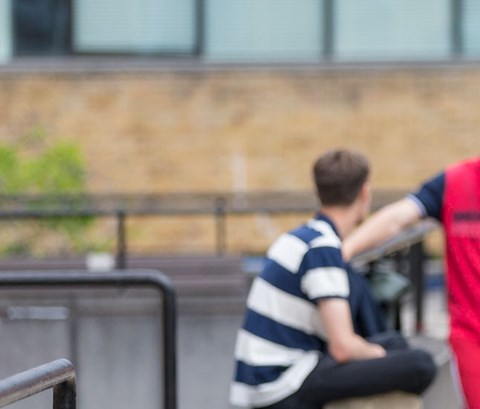 Four students walk on campus, talking and smiling
