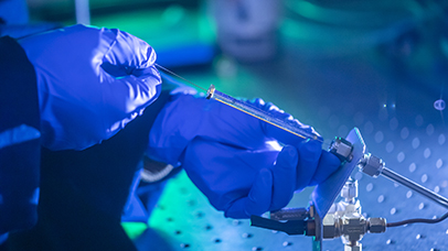 A syringe handled by a scientist's hands in surgical gloves