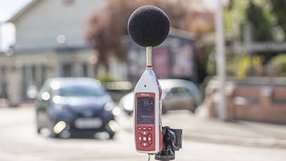 A noise pollution monitoring device with a microphone attached situated by a roadside