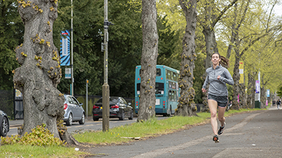 A runner exercising alongside a road filled with traffic