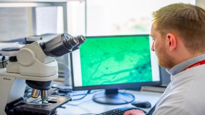Image of a scientist examining a computer image from a slide through a microscope