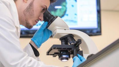 A man looks into a microscope