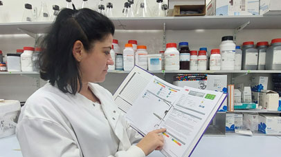 Technician wearing a white lab coat and reading health and safety instructions.